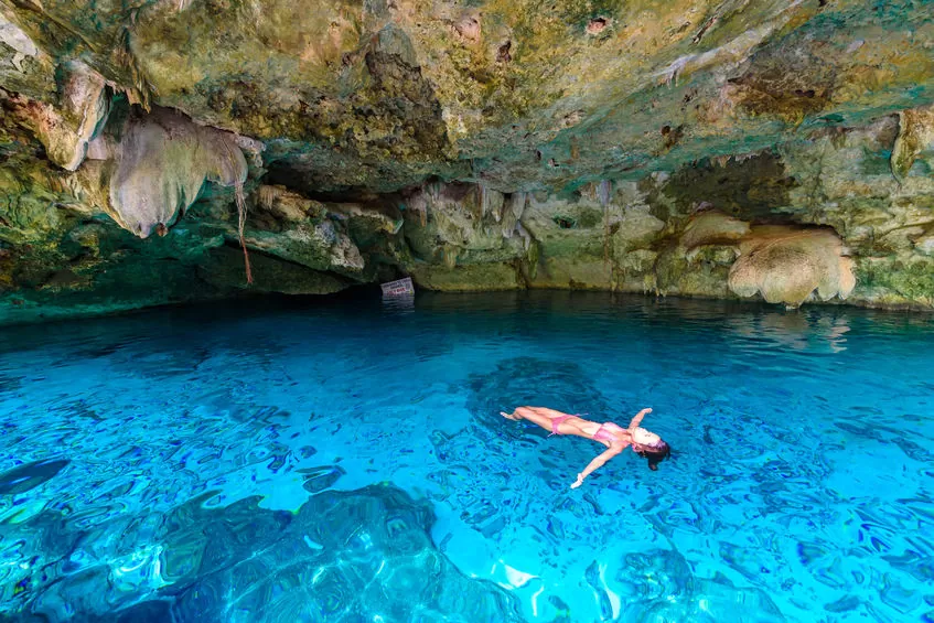 Snorkeler floating in the clear water and cave roof of Cenote Dos Ojos near Tulum