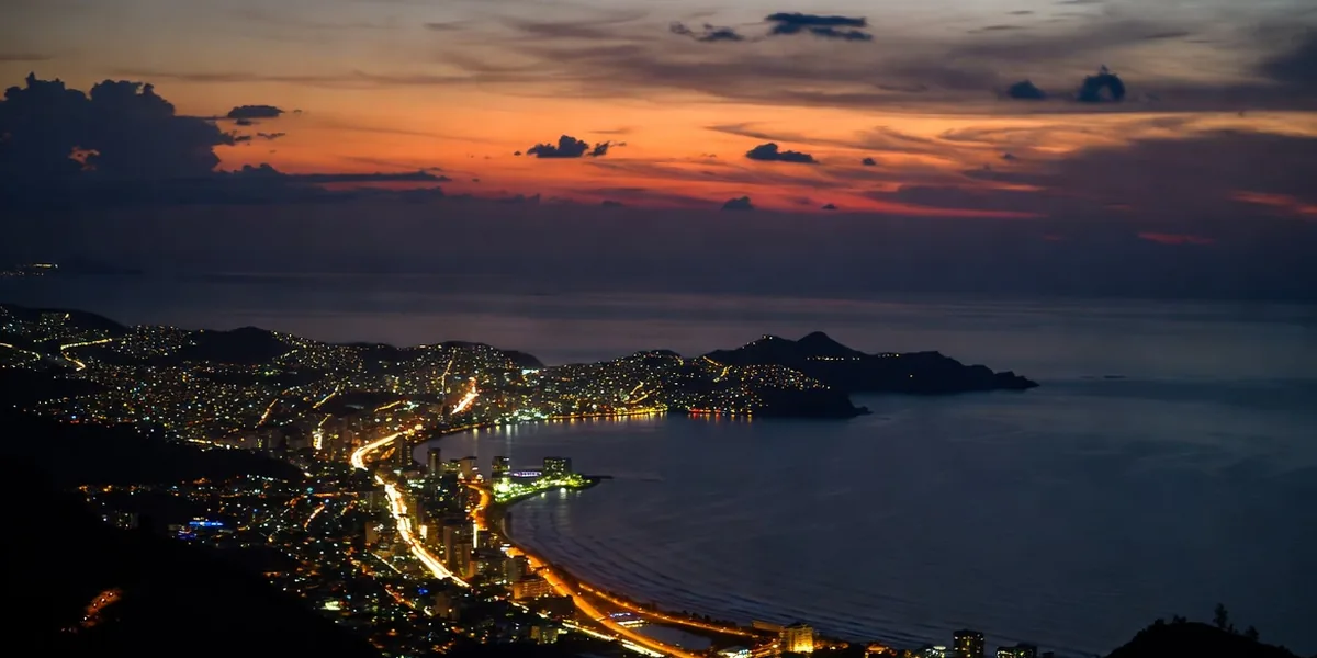 Acapulco Bay at dusk from the hills, the curve of the Costera lights meeting the dark Pacific