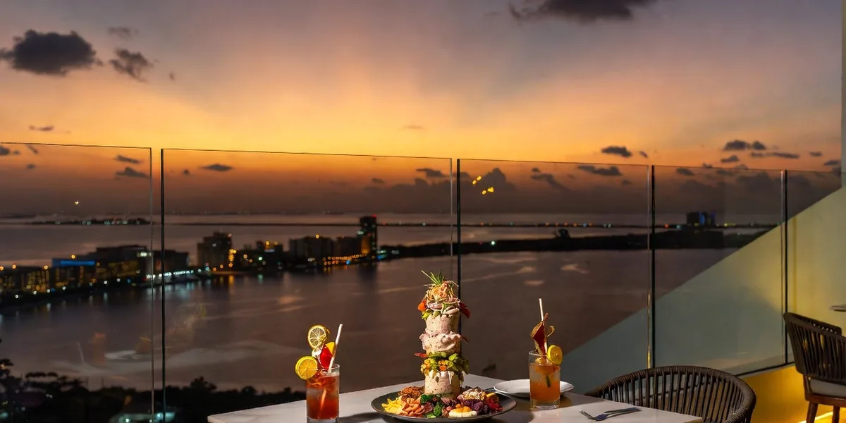 Ceviche tower and cocktails at a rooftop table overlooking the Cancún lagoon at sunset