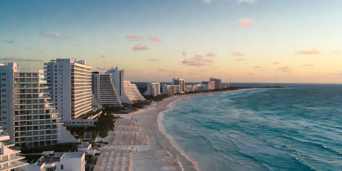 Beachfront resorts lining the white sand of Cancún's Hotel Zone at golden hour