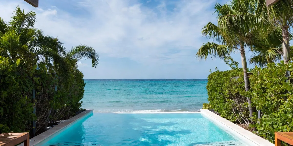 Secluded adults-only infinity pool screened by tall hedges at a Mexican beach resort — no people