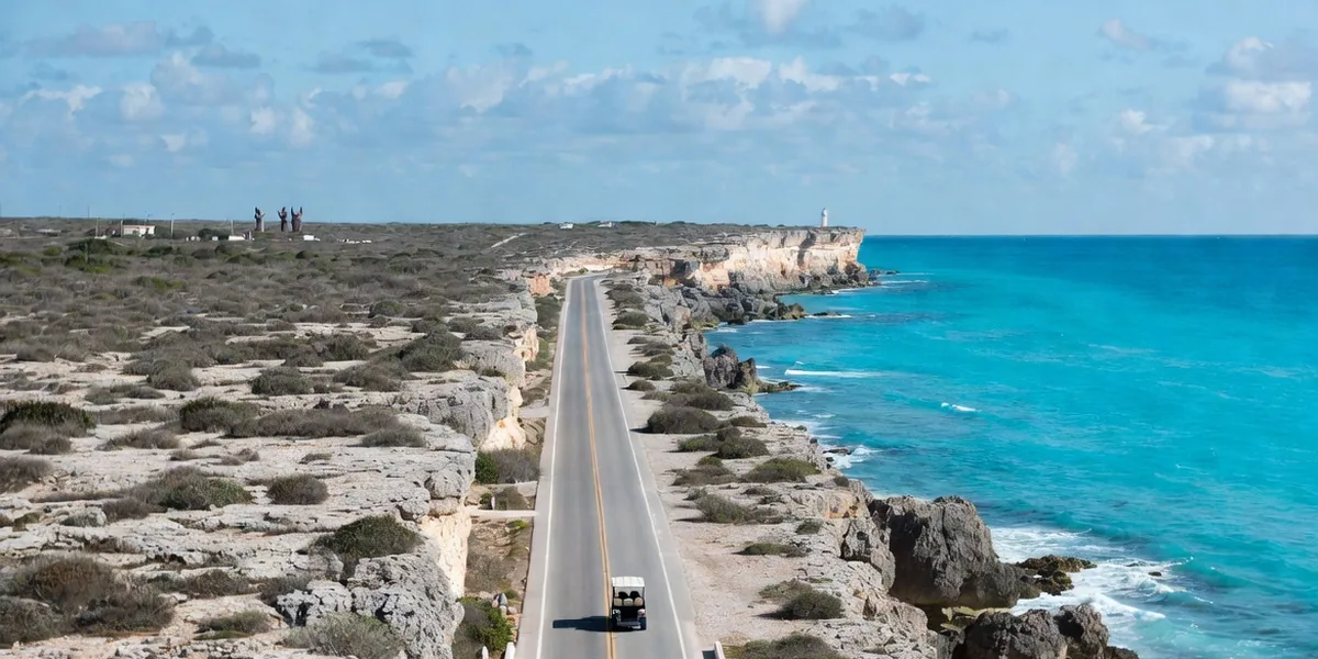 Golf cart on the Punta Sur coastal road of Isla Mujeres with Caribbean cliffs behind