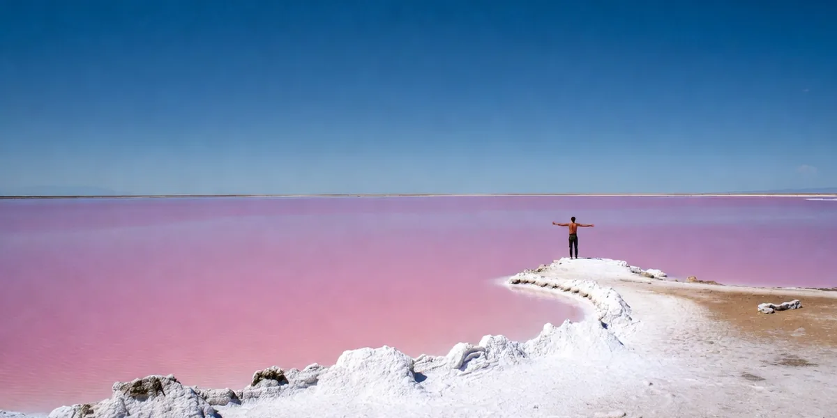 Bright pink salt evaporation lakes at Las Coloradas Yucatán under midday sun with white salt mounds on the shore