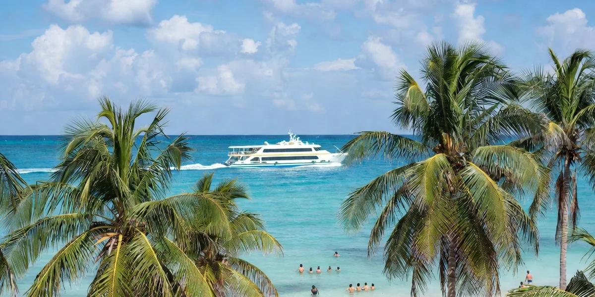 Palm-lined Playa del Carmen beach with the Cozumel ferry crossing the Caribbean offshore
