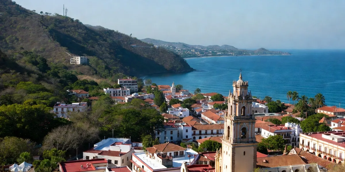 The crowned tower of the Guadalupe church above red-tile rooftops with Banderas Bay behind, Puerto Vallarta