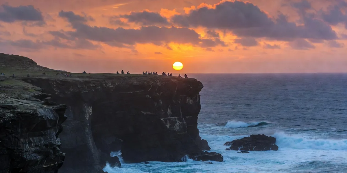 People watching the sun set into the Pacific from the rocky headland of Punta Cometa, Oaxaca