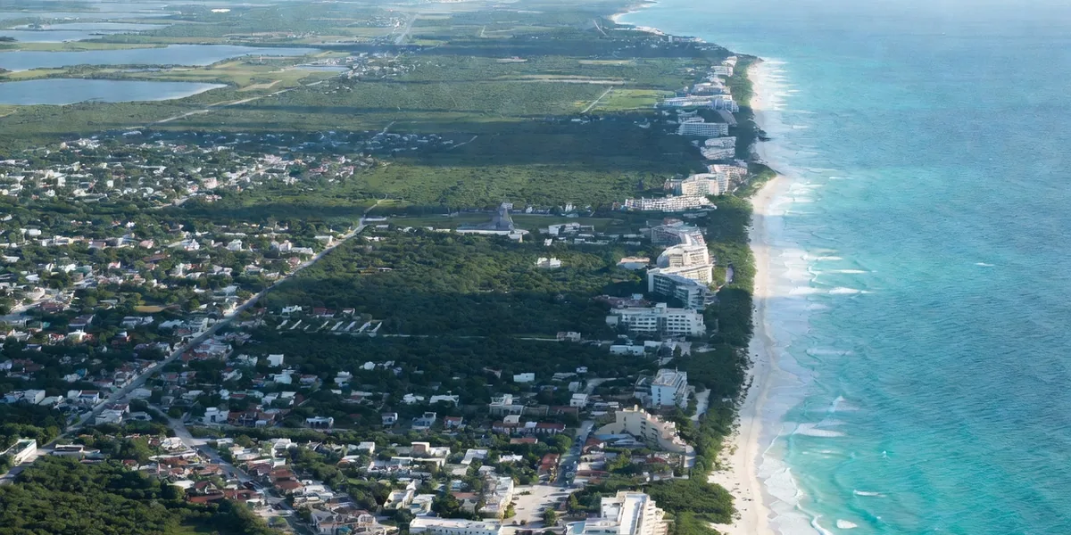 Oblique aerial showing Tulum's layout — town grid, jungle road and the beach hotel strip