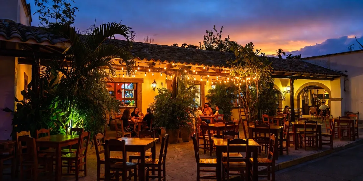 Open-air restaurant tables under string lights on a street in Tulum pueblo at dusk